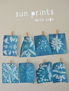 blue and white snowflakes are hung on clothes pins with the words sun prints with kids