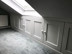 an empty room with white cupboards and a skylight