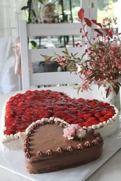 a heart shaped cake sitting on top of a table next to a vase with flowers