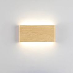 a light that is on the side of a white wall with a wooden block in front of it