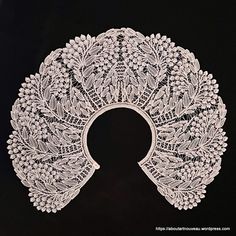 a white lace doily with leaves and berries on it's side, against a black background