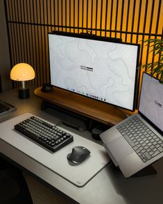 a laptop computer sitting on top of a desk next to a keyboard and mouse in front of a monitor