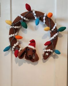 a crocheted wreath with a dog wearing a santa hat and lights on it