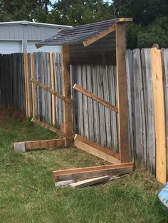 a wooden shed sitting in the grass next to a fence