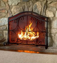 a fire is burning in a fireplace with rocks on the wall and floor behind it