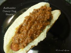 a chili dog bun on a black plate with the words authentic coney dog sauce