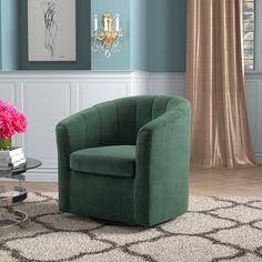 a green chair sitting on top of a rug next to a table with pink flowers