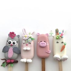 four popsicles decorated with animals and flowers on wooden sticks in front of a white background