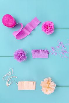 pink and white hair accessories laid out on a blue background, including a brush, comb, flower headbands, beads, and other items