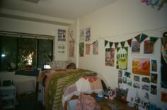 a bed room with a neatly made bed and lots of pictures on the wall above it