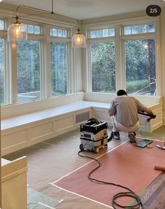 a man working on the floor in front of large windows