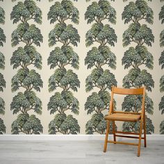 a wooden chair sitting in front of a wall with a large tree pattern on it