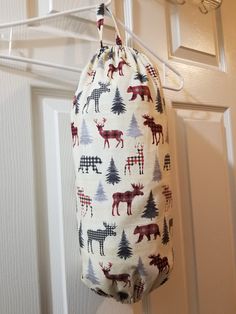 a bag hanging from a hook on a door with christmas trees and deers all over it