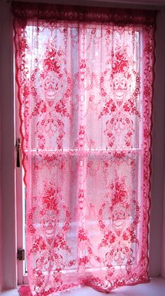 a pink window curtain in front of a white window with red lace on the curtains