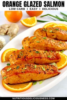 orange glazed salmon on a white plate with lemons and garlic garnishes