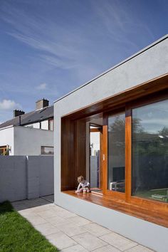 a small child sitting on the window sill of a house