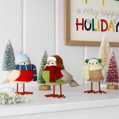 three little birds are standing in front of a holiday card on the mantel shelf