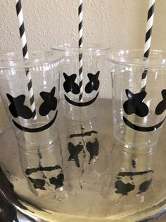 four glasses with black and white striped straws in them sitting on a metal tray