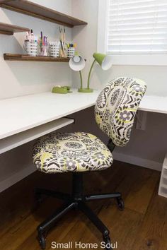 an office chair sitting in front of a desk with shelves on the wall behind it