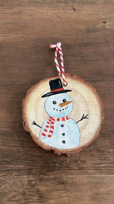 a snowman ornament hanging on a wood slice