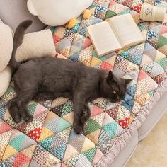 a black cat laying on top of a bed next to pillows