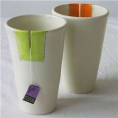 two cups with tags on them sitting next to each other in front of a white background