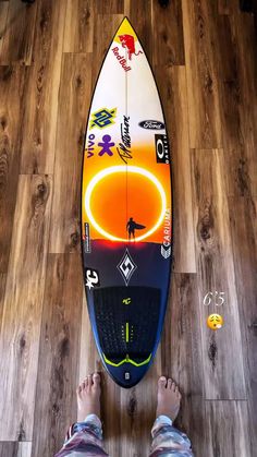 a person standing next to a surfboard on top of a wooden floor