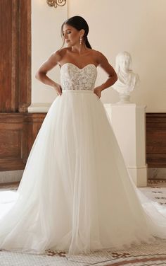 a woman in a wedding dress posing for the camera with her hands on her hips