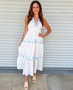 a woman standing in front of a garage door wearing a white dress with blue flowers