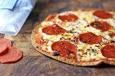 a pepperoni pizza sitting on top of a wooden cutting board next to a bag of cheese