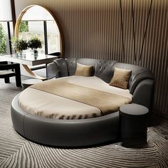 a large round bed sitting in the middle of a living room next to a window