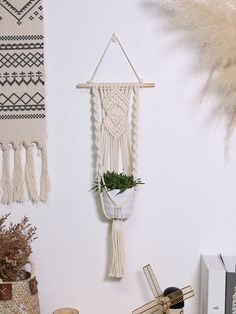 a white wall hanging on the side of a wall next to plants and other items