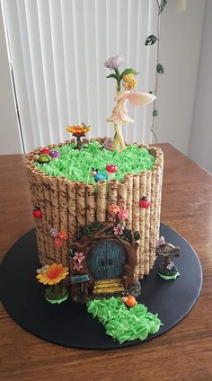 a cake made to look like a wicker house with fairy figurines on top