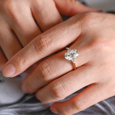 a woman's hand with a diamond ring on top of her finger and the other hand holding an engagement ring