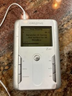 an electronic device sitting on top of a marble counter next to a corded charger