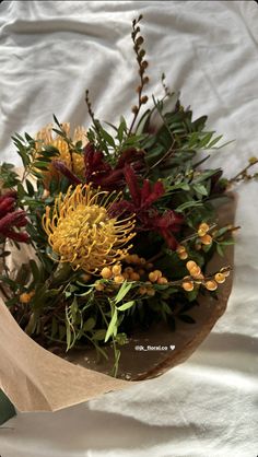 a bunch of flowers that are sitting on a white sheet with some paper around them