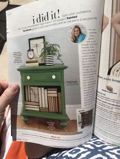 a person is holding up a magazine with an image of a green cabinet on it