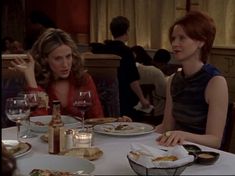 two women sitting at a table with plates of food