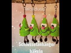 three green knitted christmas trees hanging from chains with words in german above them that read,'wotidusee schlusselschalnhangerer haikenn