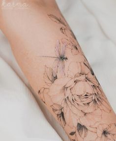 a woman's arm with flowers and a dragonfly on it