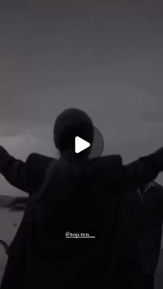 a man standing in front of the ocean with his arms outstretched