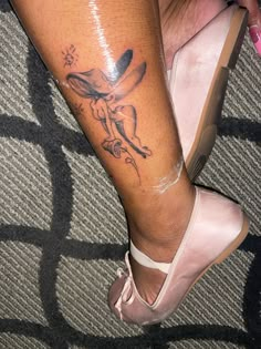 a woman's leg with a tattoo on it and her shoe in the foreground