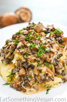 a white plate topped with mashed potatoes covered in mushrooms