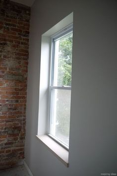 an empty room with a brick wall and window