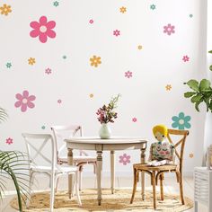 a white table and chairs in front of a wall with flower decals on it