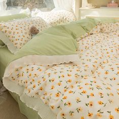 an unmade bed with yellow flowers and green sheets on it's headboard