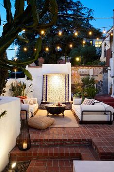 an outdoor living area with white couches and lights