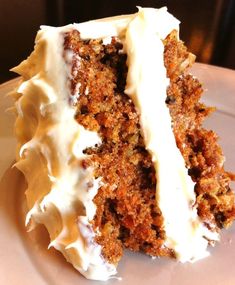 a piece of carrot cake with white frosting on a plate