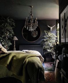 a bedroom with a chandelier hanging from the ceiling next to a bed covered in green blankets