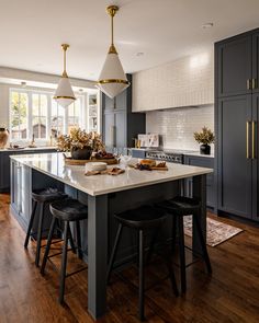 a kitchen with an island and two pendant lights hanging from it's ceiling above the counter